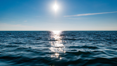 Sun on blue sky is reflected on water