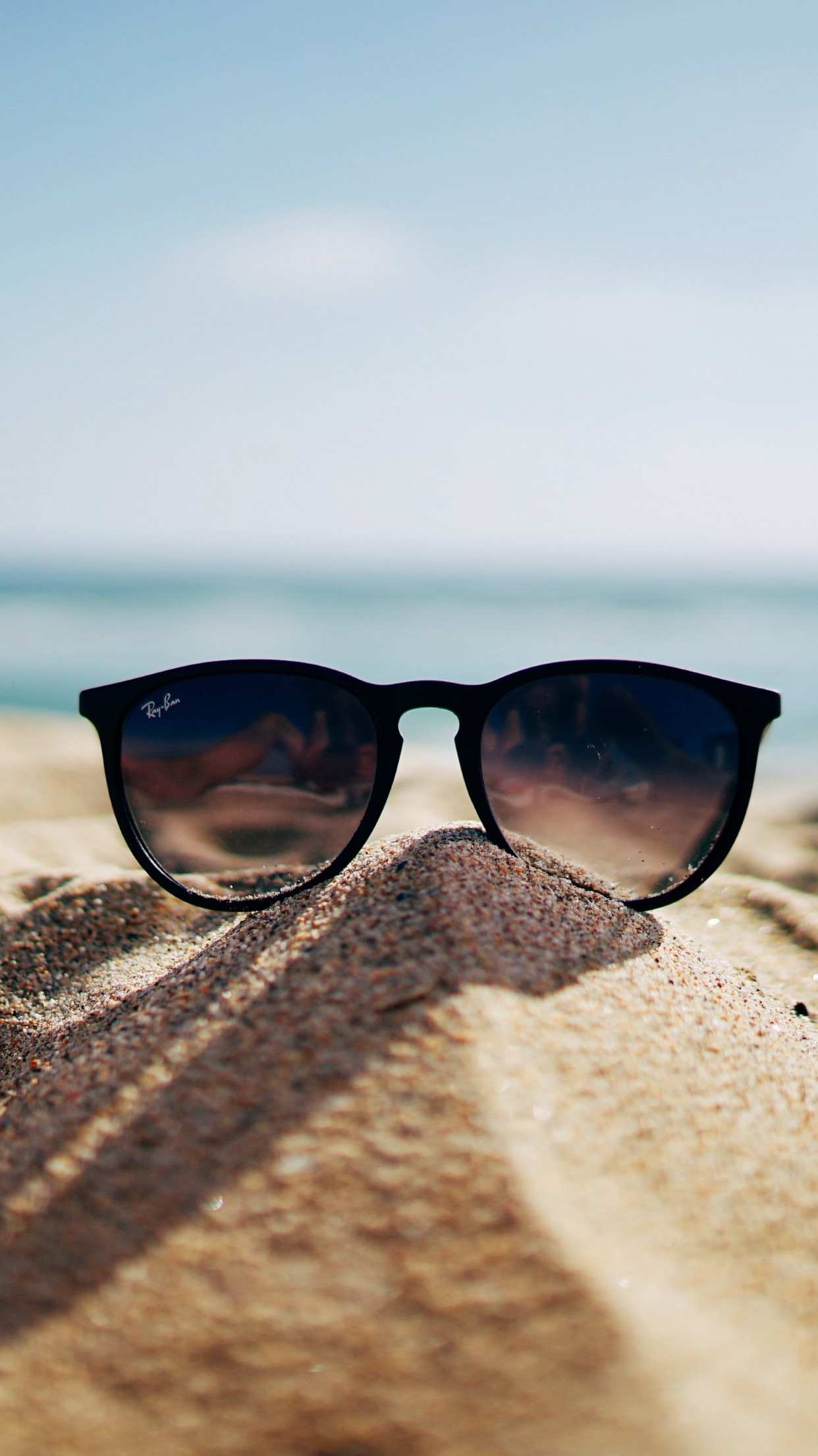 Ray Ban sunglasses on hot sand beach wallpaper 1242x2208
