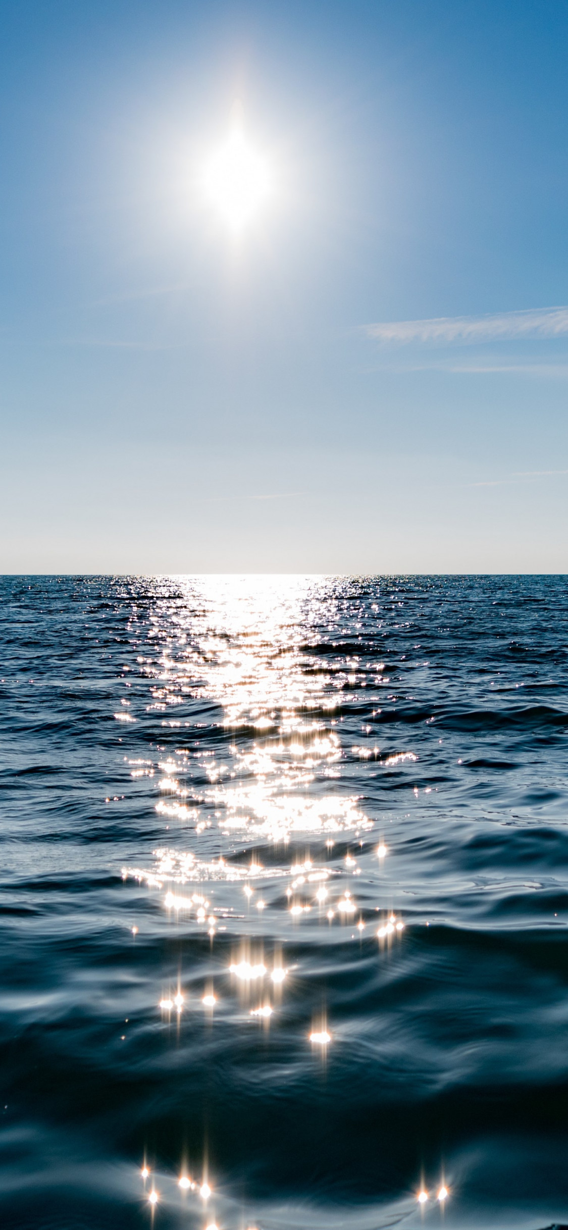 Sun on blue sky is reflected on water wallpaper 1125x2436